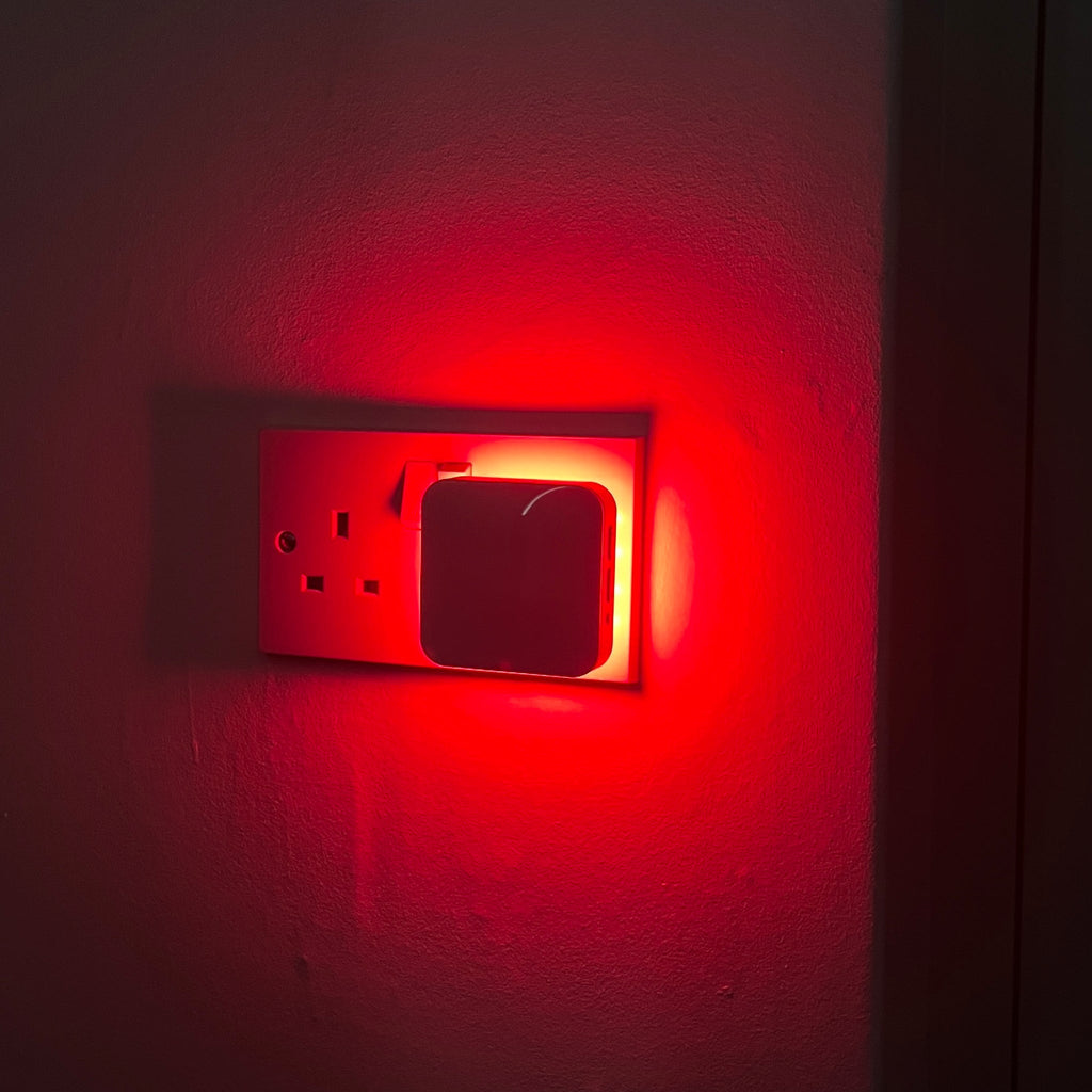 Driftback red night light glowing in a hallway socket
