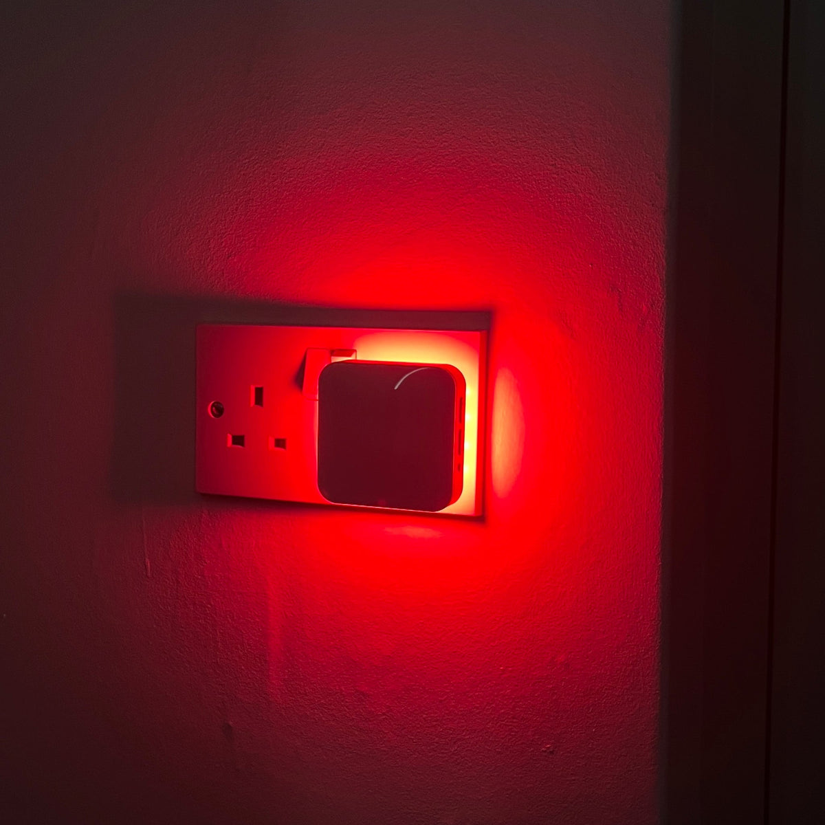 Driftback red night light glowing in a hallway socket