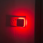 Driftback red night light glowing in a hallway socket