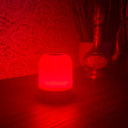 The Driftback sleep lamp glowing 670nm red on a bedside table