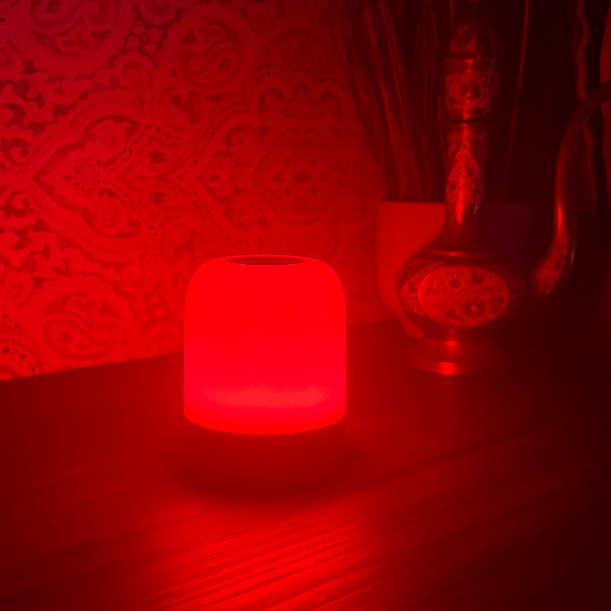 The Driftback sleep lamp glowing 670nm red on a bedside table