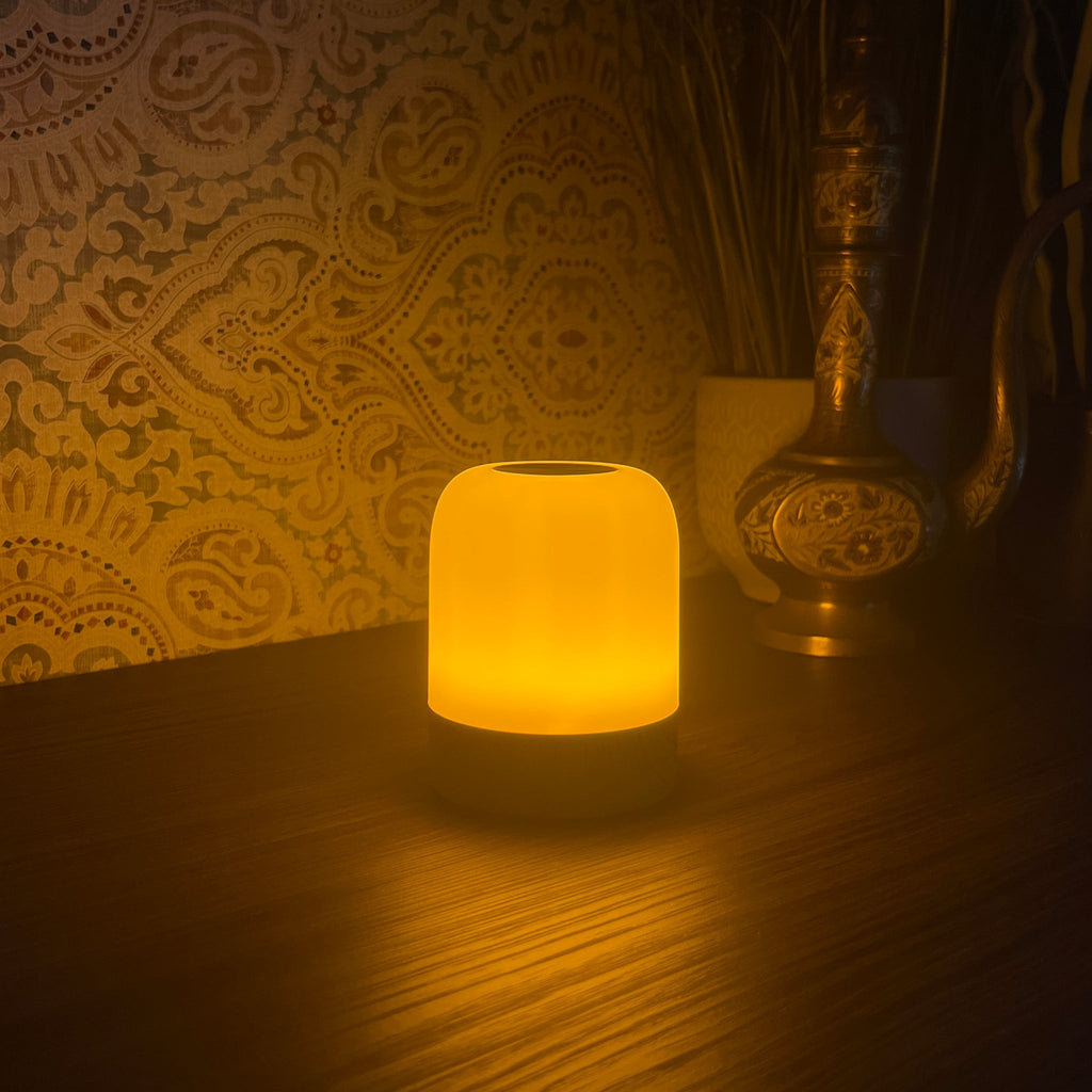 The Driftback sleep lamp glowing warm amber on a bedside table