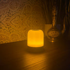 The Driftback sleep lamp glowing warm amber on a bedside table